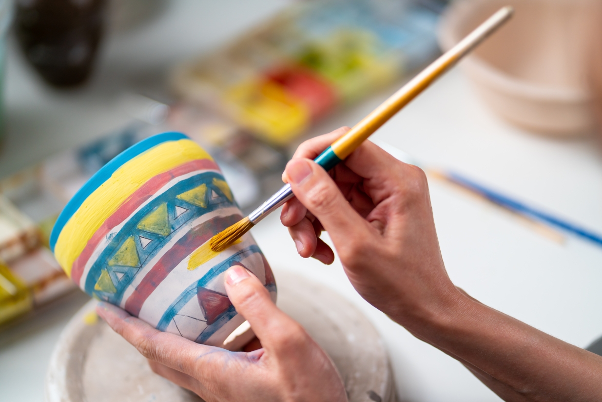 Person painting a plant pot