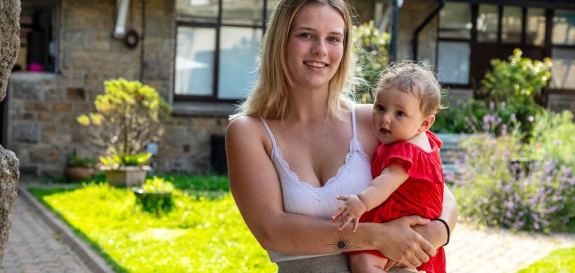 Samara holding Rozie-Mae and smiling at the camera.