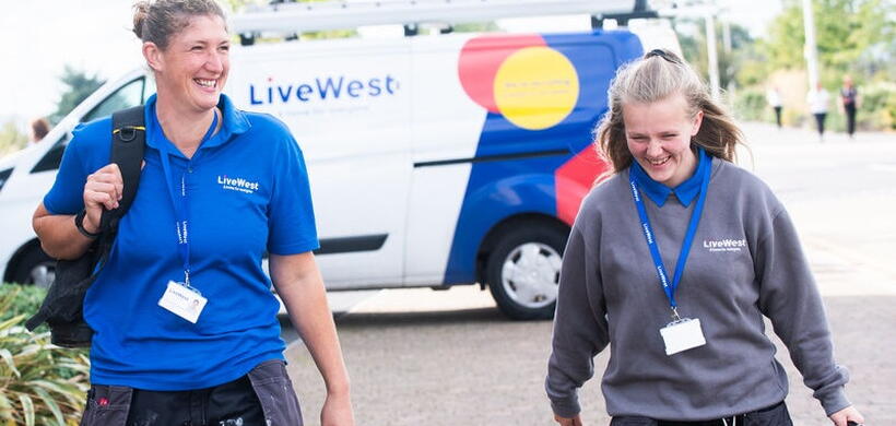 Gayle with another colleague carrying a tools from a van. 