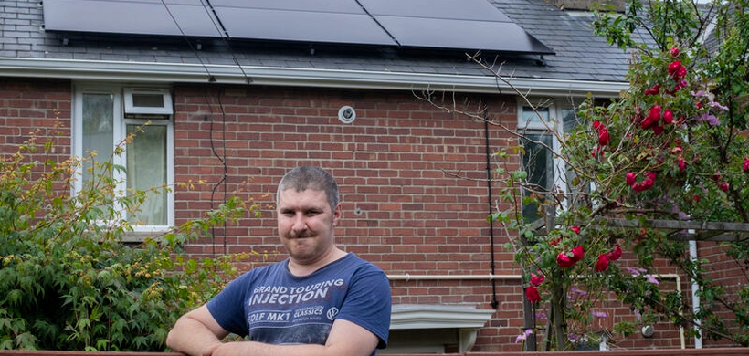 Robert stood outside his home with solar panels.