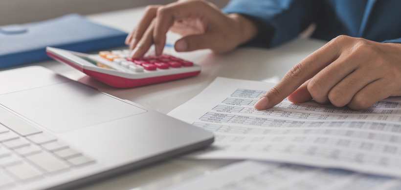 Person at desk with calculator and finance documents