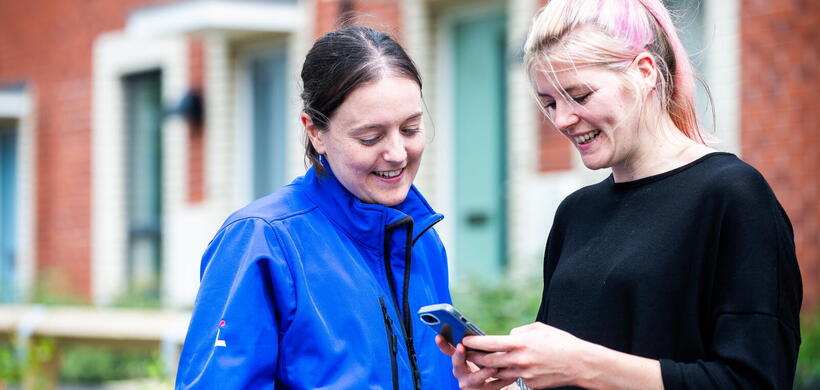 LiveWest colleague with a customer looking at a phone. 