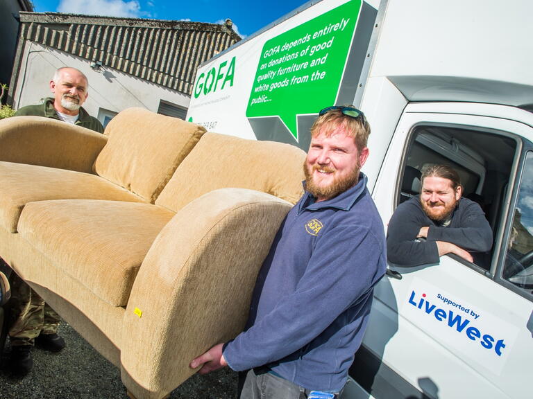 Men smiling and carrying a sofa