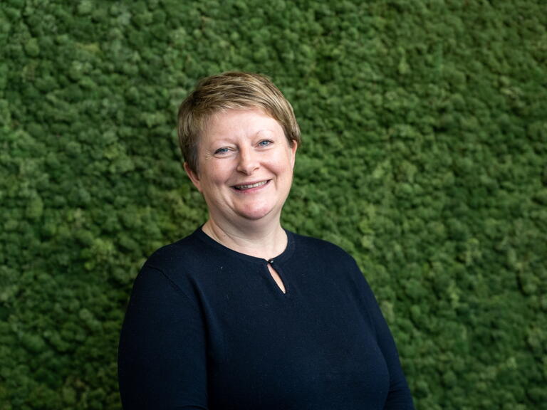Glynnis smiling with a green leafy background