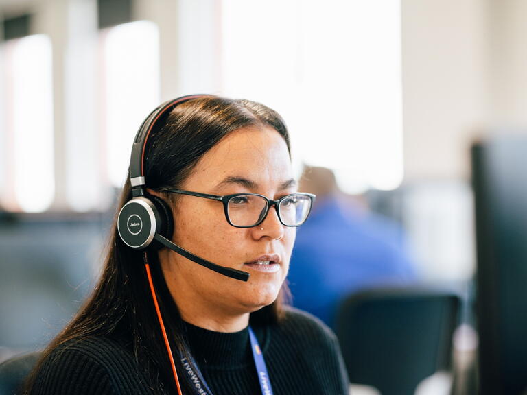 LiveWest colleague using a headset to speak on the phone. 