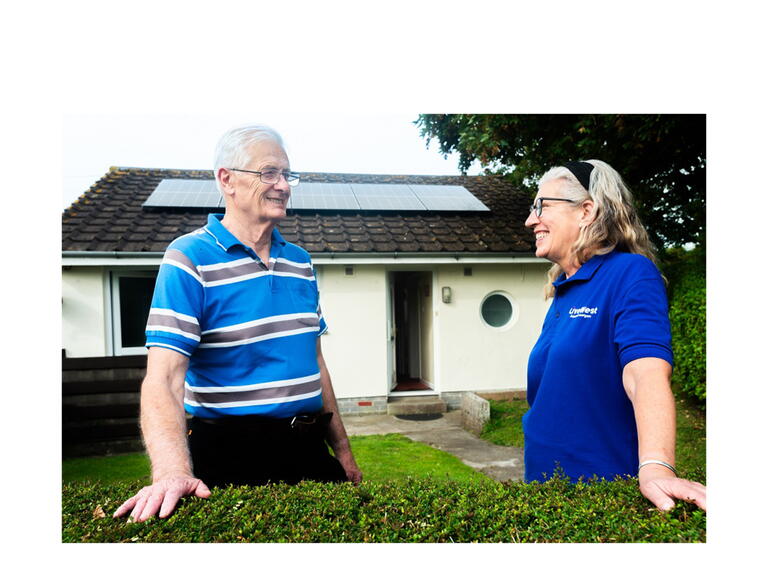 Tom Kingdom smiling outside of his home with new solar panels. 