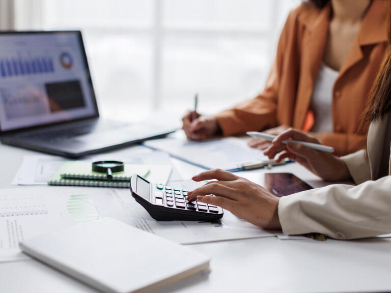 People sitting at desk with laptop and calculator