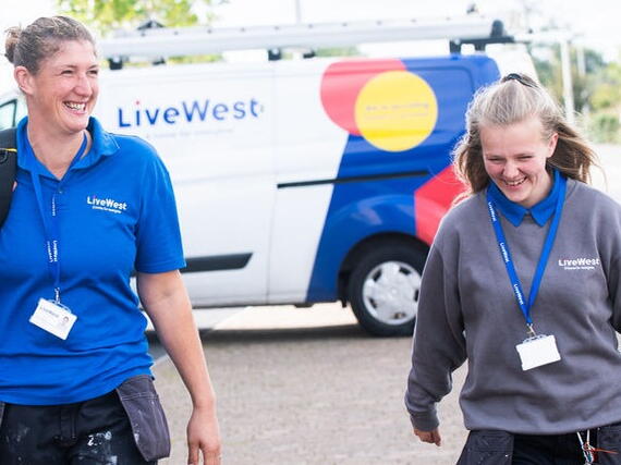 Gayle with another colleague carrying a tools from a van. 