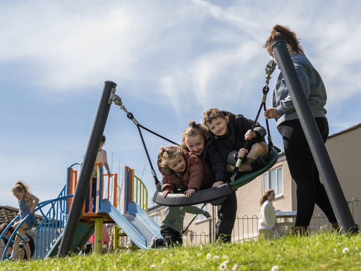 Three children swinging on a new round swing.