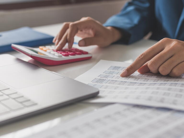 Person at desk with calculator and finance documents