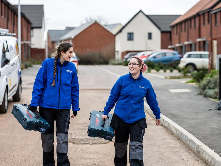 LiveWest colleagues carrying toolboxes on a street. 