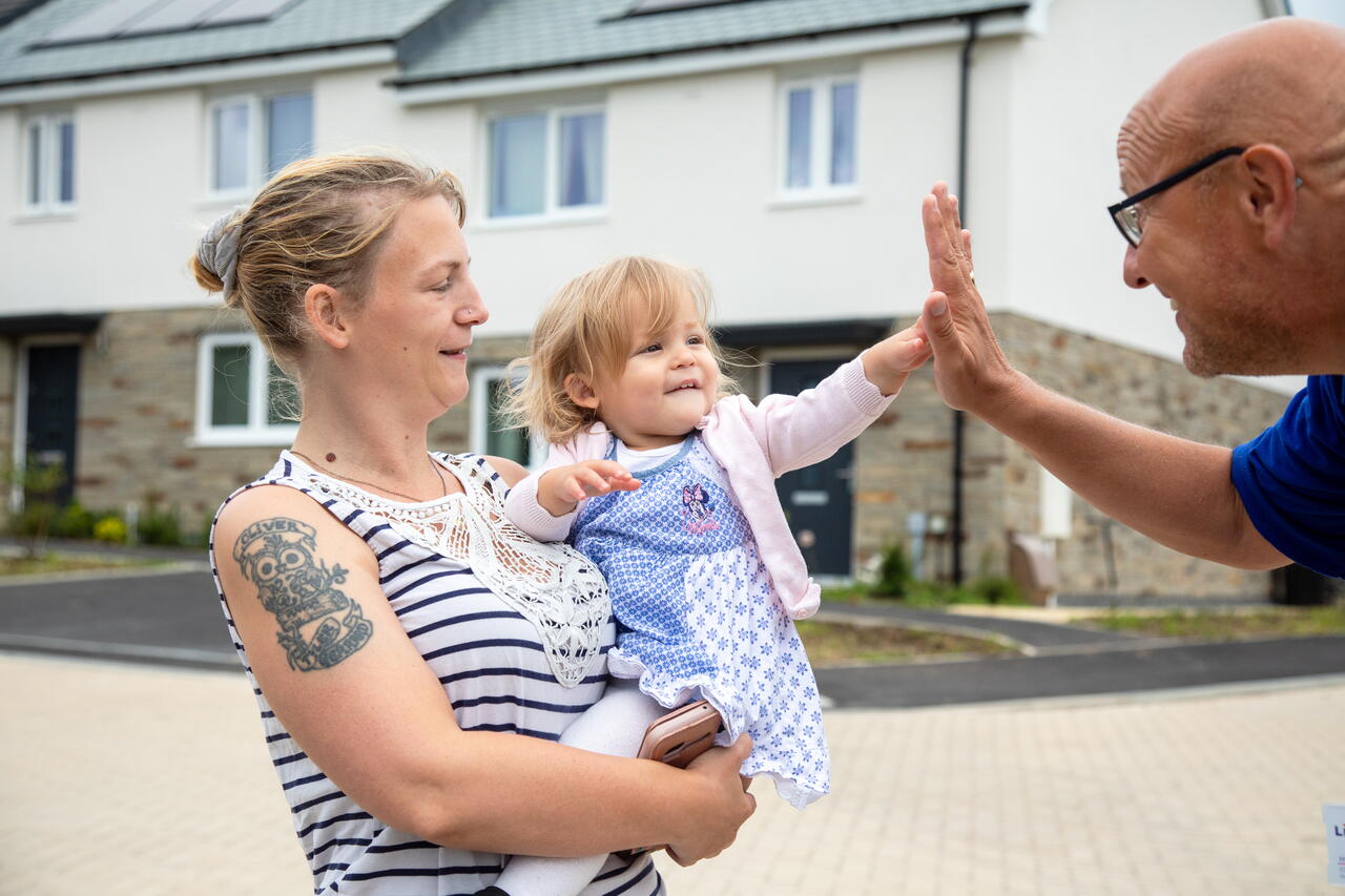 Image of a LiveWest colleague high-fiving a resident and her young daughter