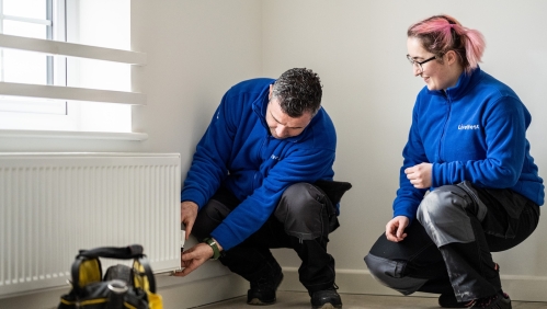 Two LiveWest colleagues carrying out a repair to a radiator in a customer home. 