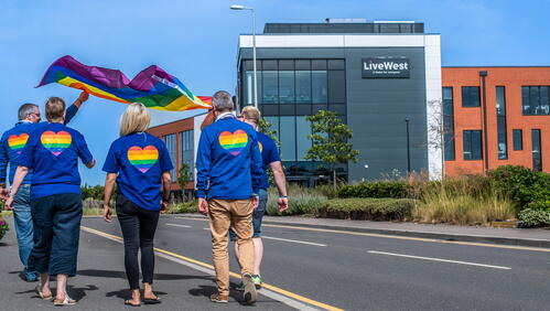 Image of LiveWest colleagues walking towards our office, wearing LGBTQIA+ flags on their backs.