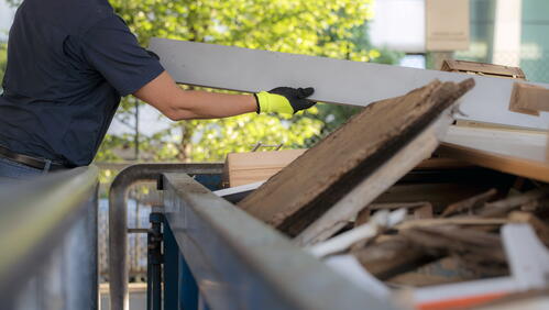 Image of a man putting large items in a skip