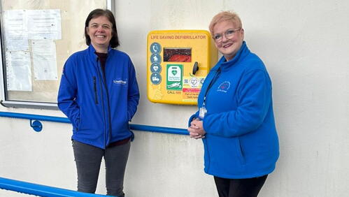 Image of LiveWest colleague and community member smiling in front of the new defibrillato