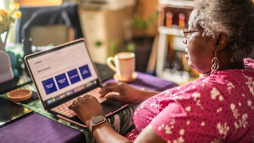 A person is using a laptop at a table in a warm, homey room.